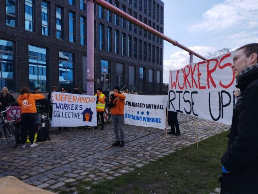 Gemeinsam gegen Arbeitsrechtsverletzungen: Arbeiterinnen und Arbeiter von Wolt, Lieferando, Flink sitzen zusammen